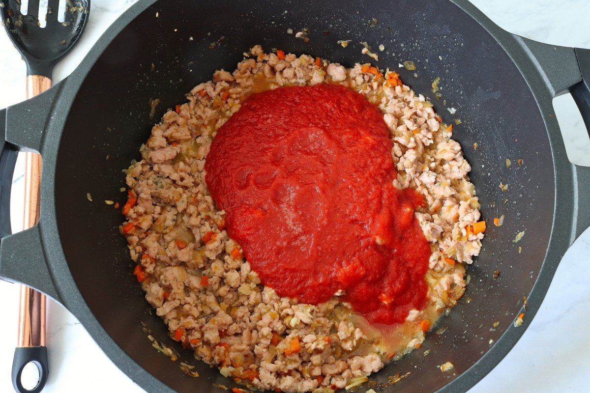 Añadir el tomate al pastel gratinado de patata y carne picada de pollo