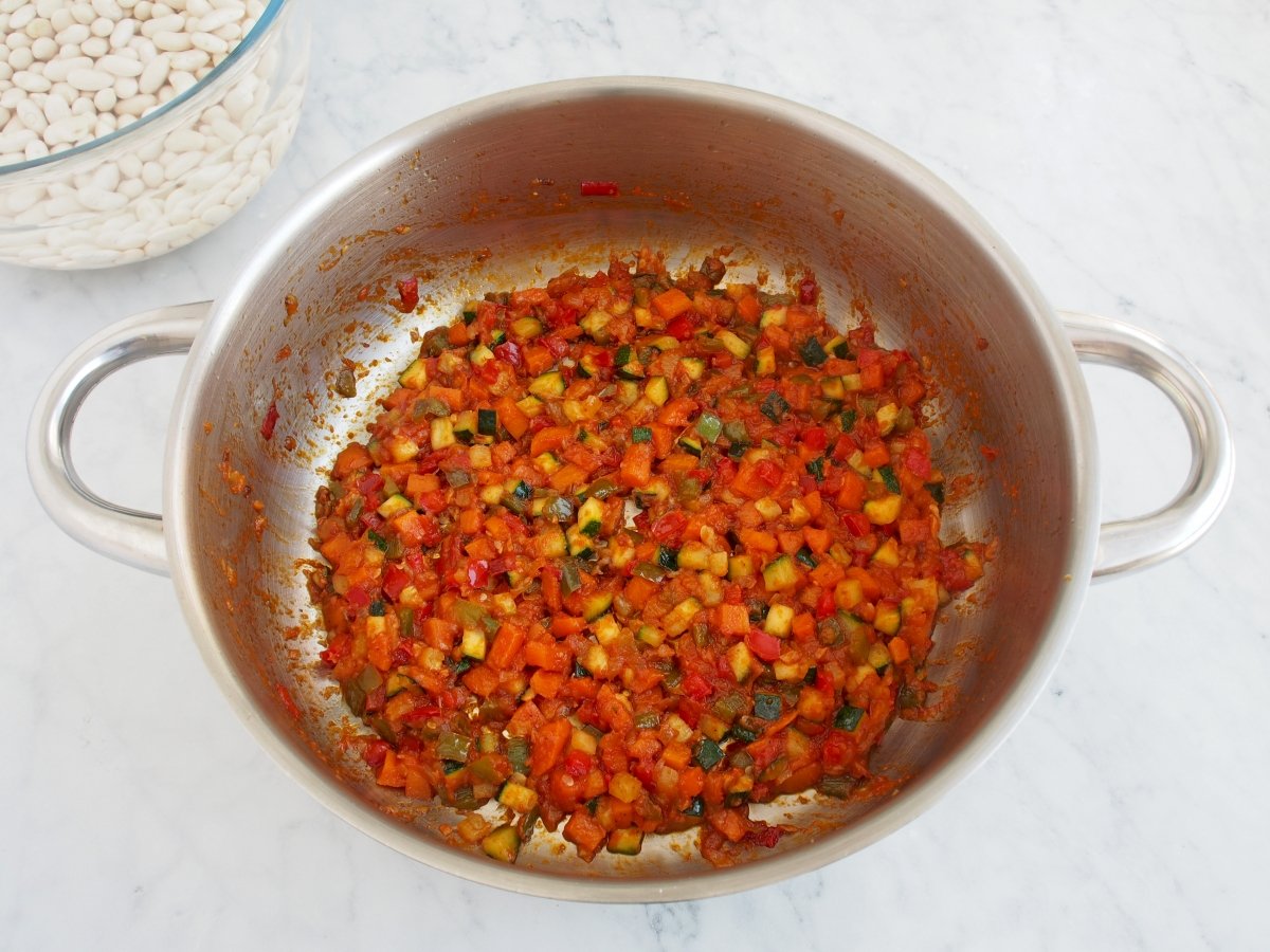 Añadir el tomate al sofrito de las alubias blancas con verduras