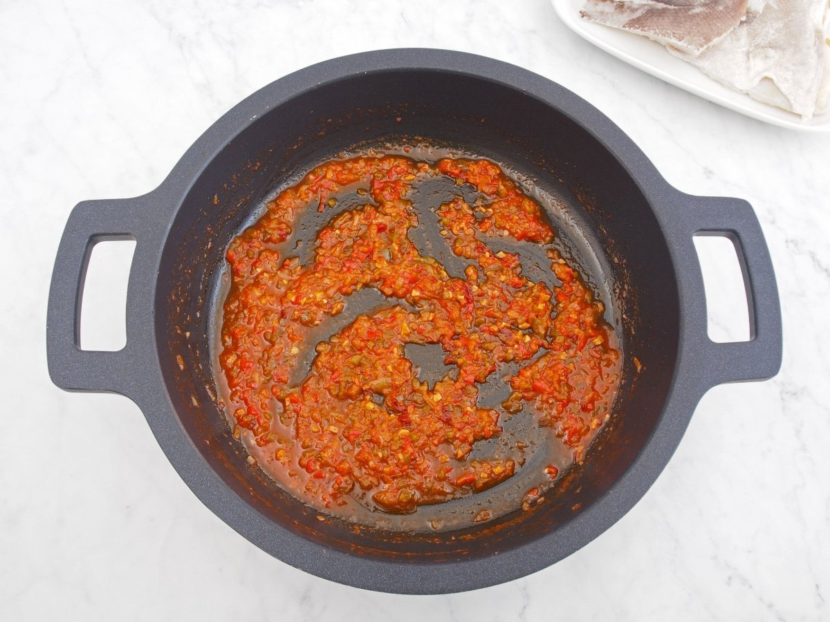 Añadir el tomate al sofrito del arroz con bacalao