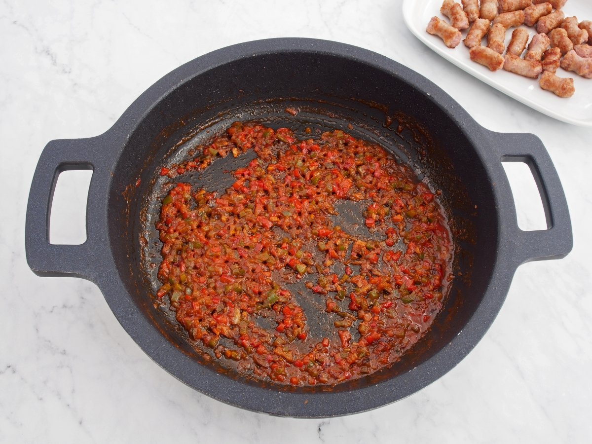 Añadir el tomate al sofrito del arroz con salchichas