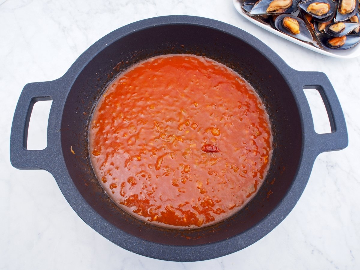 Añadir el tomate frito al sofrito de los mejillones en salsa picante