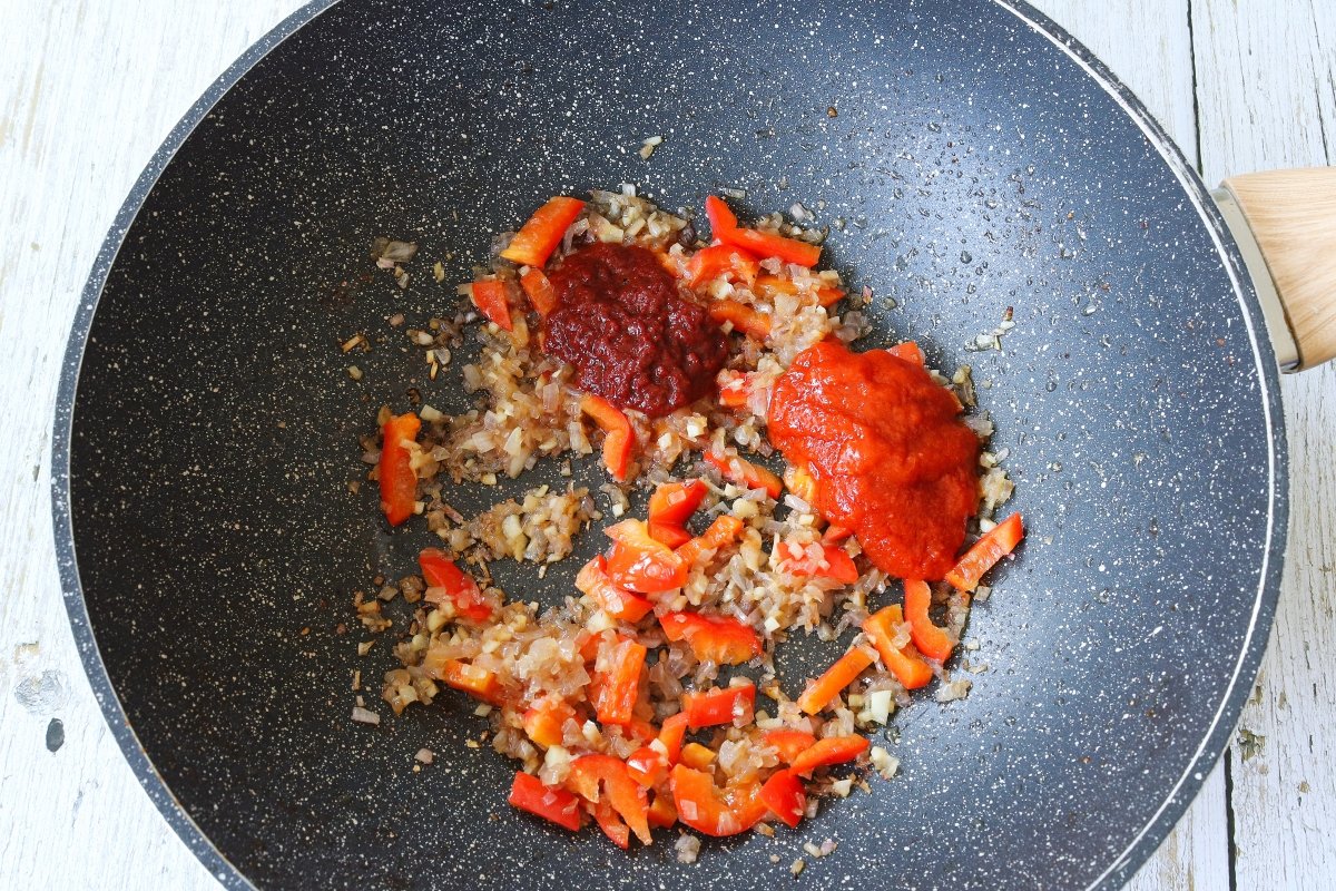 Añadir el tomate frito y la carne de pimiento choricero al arroz con carne