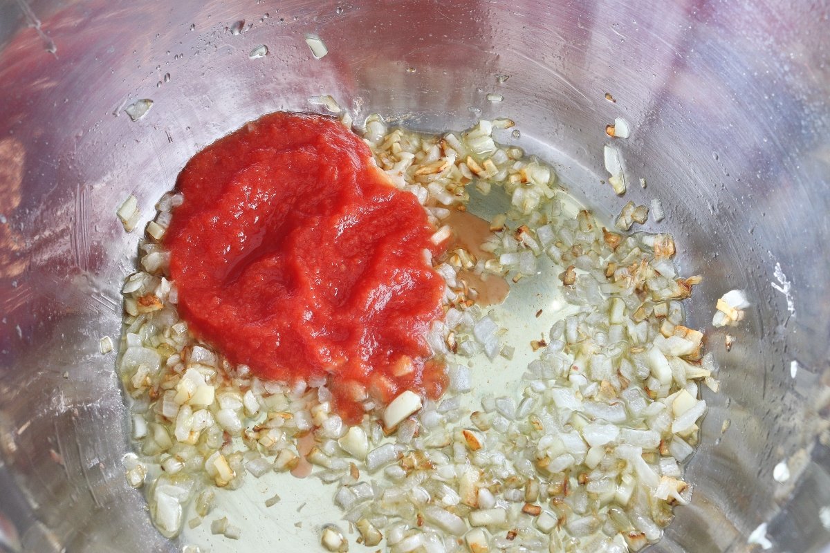 Añadir el tomate para el sofrito de la sopa de coliflor