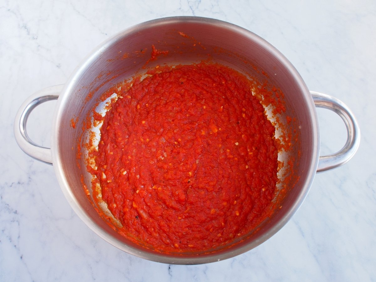 Añadir el tomate triturado y cocinar la salsa