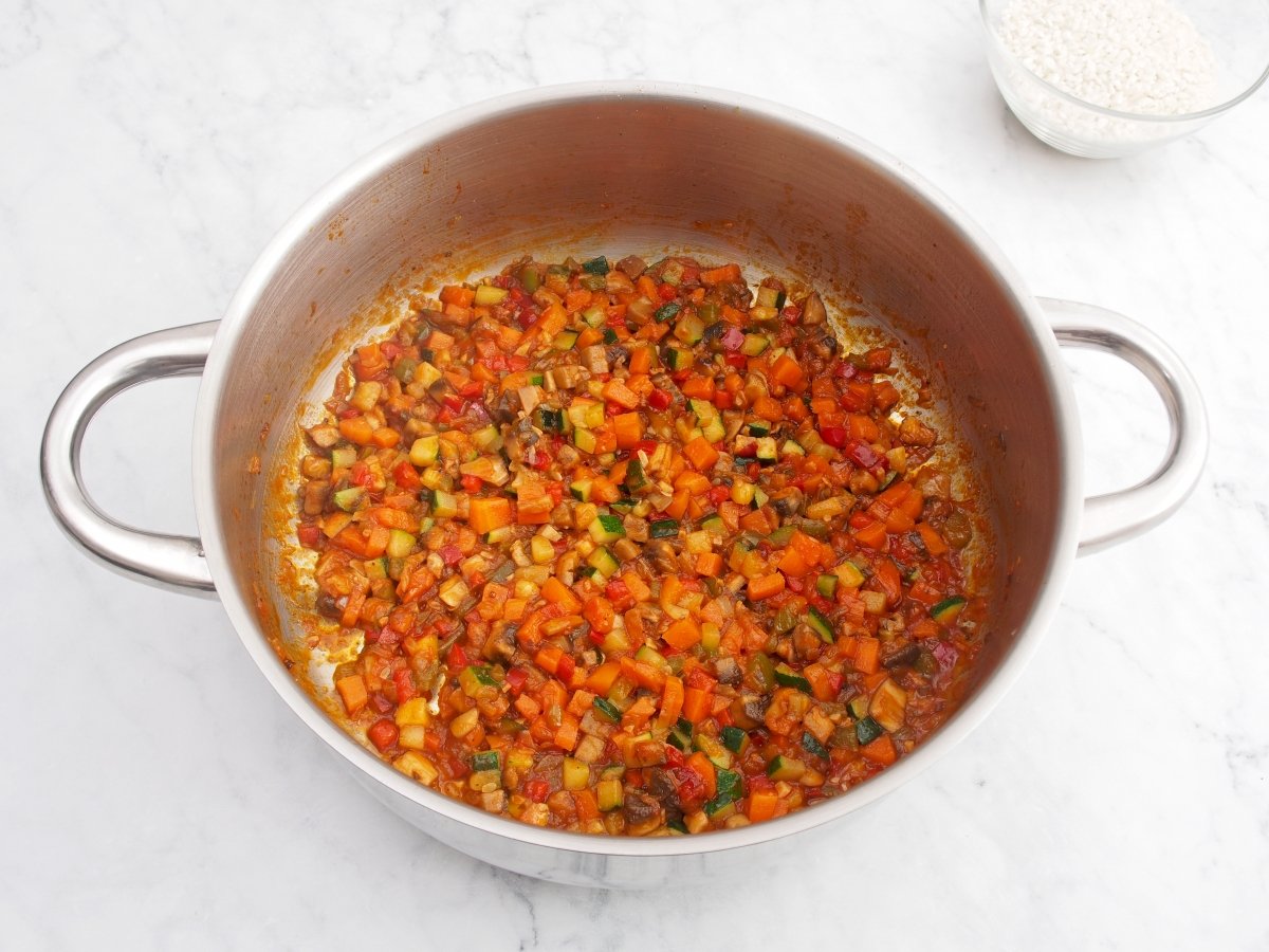 Añadir el tomate y el vino al sofrito del arroz caldoso de verduras