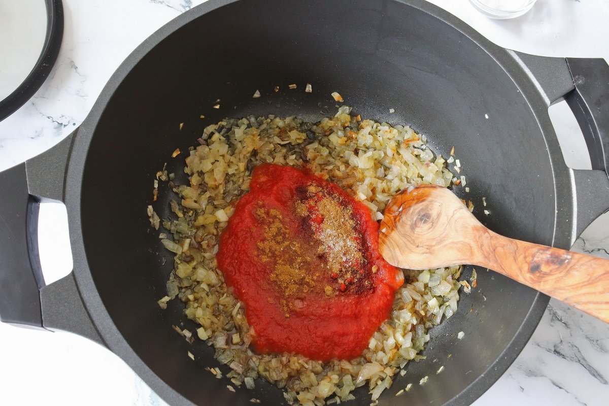 Añadir el tomate y los condimentos para el potaje de garbanzos con bacalao y espinacas