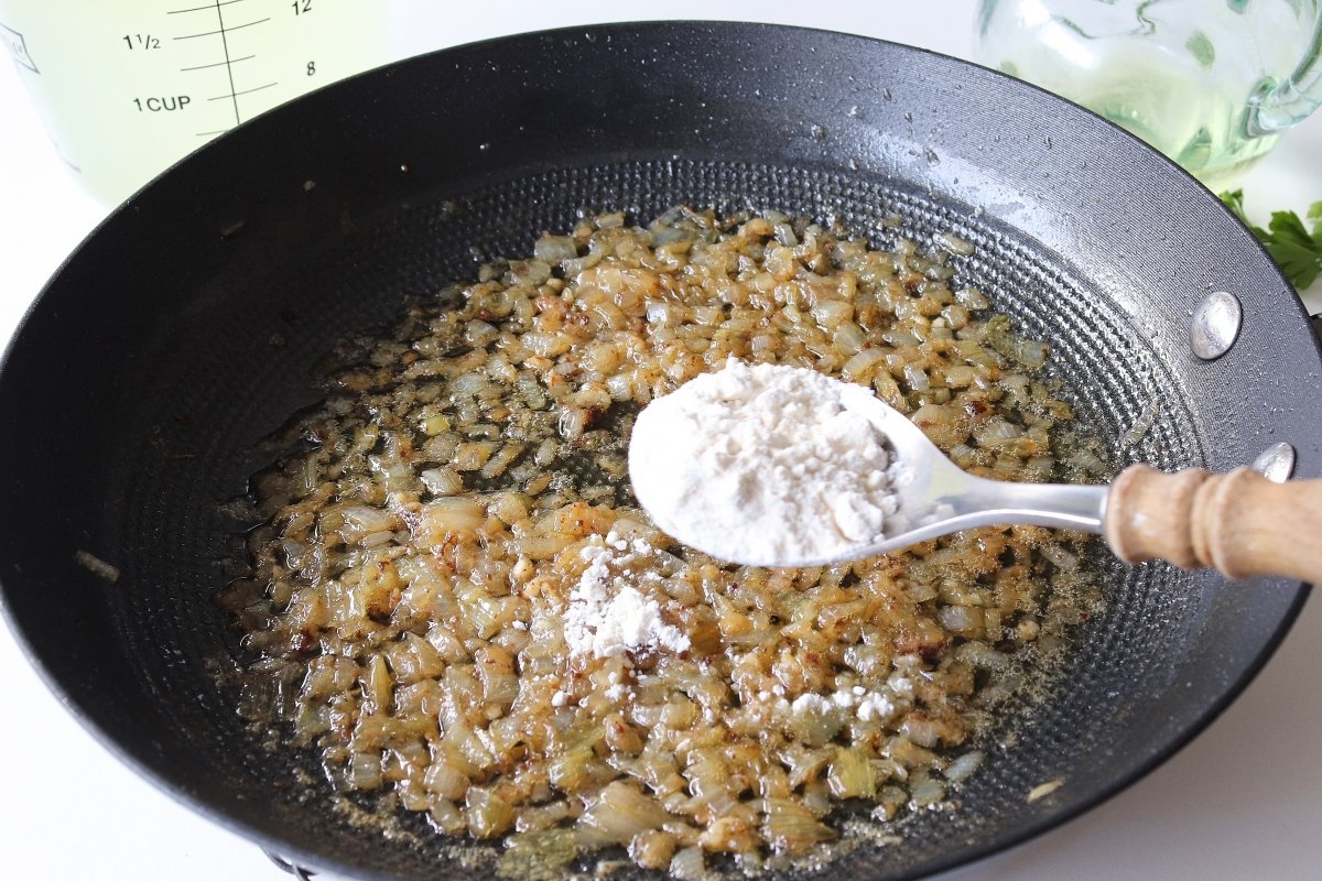 Añadir harina al sofrito para las albóndigas de carne en salsa verde