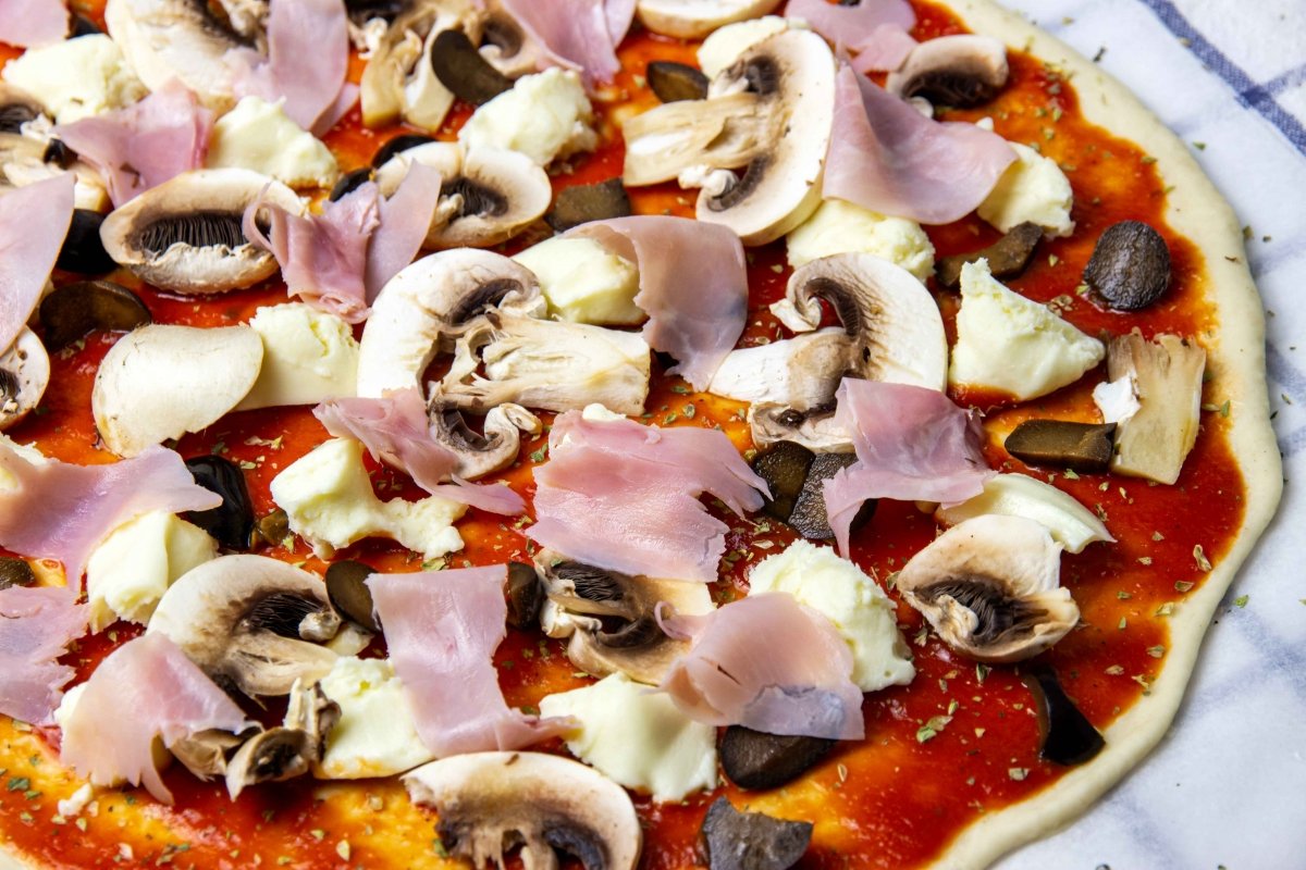 Añadir jamón y aceitunas a la pizza romana