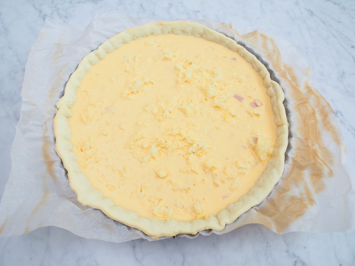 Añadir la mezcla de huevos y nata a la quiche de jamón y queso