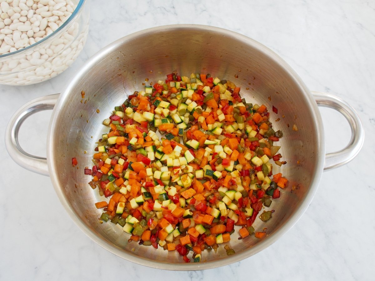 Añadir la zanahoria y el calabacín al sofrito de las alubias blancas con verduras