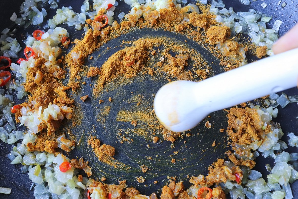Añadir las especias al sofrito para el curry de garbanzos