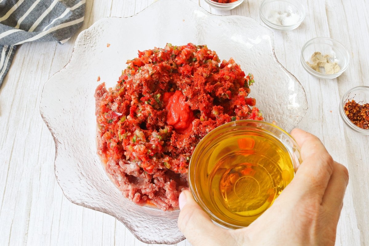 Añadir las especias, el tomate concentrado y el aceite a la carne de las lahmacun