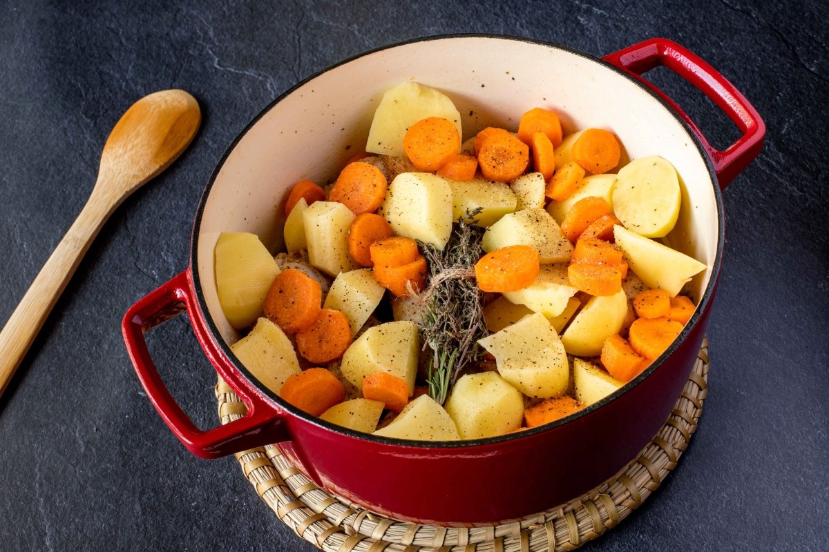 Añadir las patatas, las zanahorias y el agua para hacer el estofado de pollo con patatas y verduras
