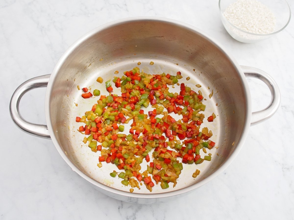 Añadir los pimientos al sofrito del arroz caldoso de verduras