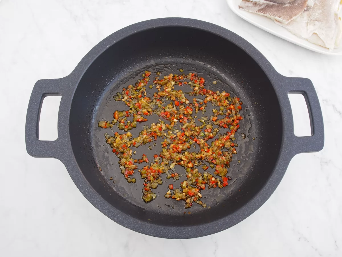 Añadir los pimientos al sofrito del arroz con bacalao