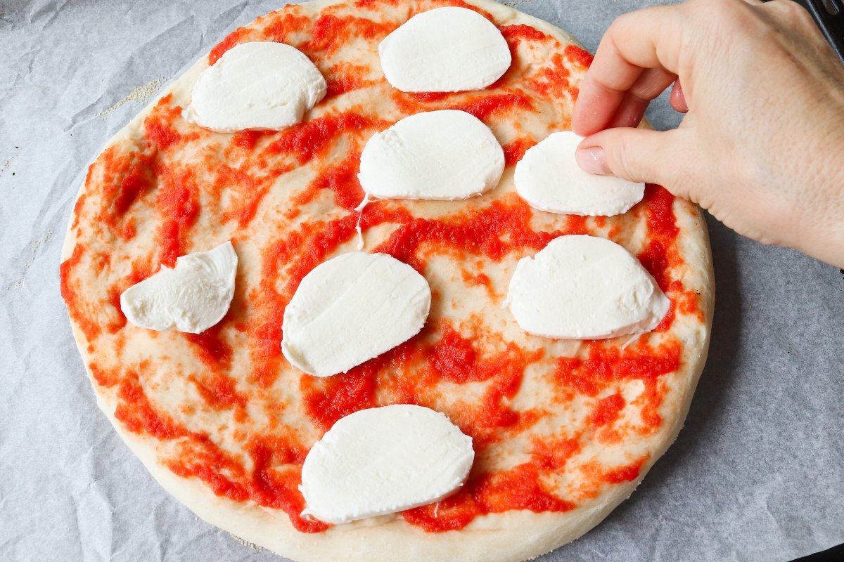 Añadir mozzarela en rodajas a la pizza margarita