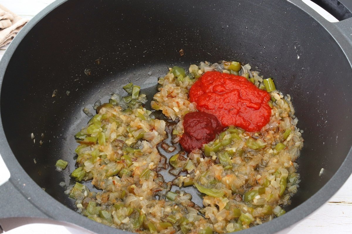 Añadir salsa de tomate y pimiento choricero al arroz con costillas de cerdo