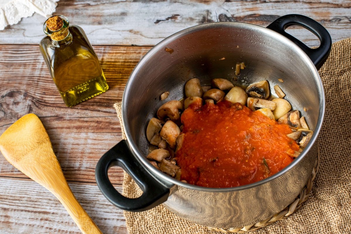 Añadir tomate a la salsa de los macarrones con champiñones, tomate y queso