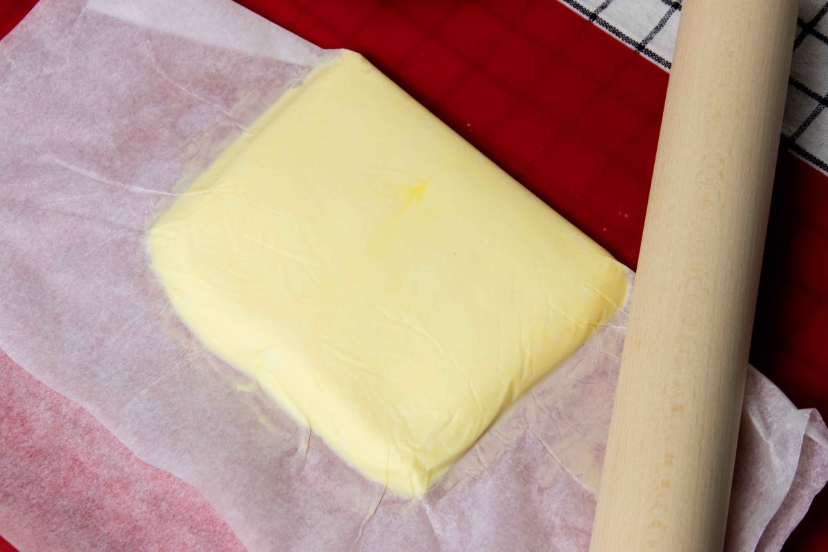 Aplastar la mantequilla en el papel de horno con el rodillo y formar una plancha