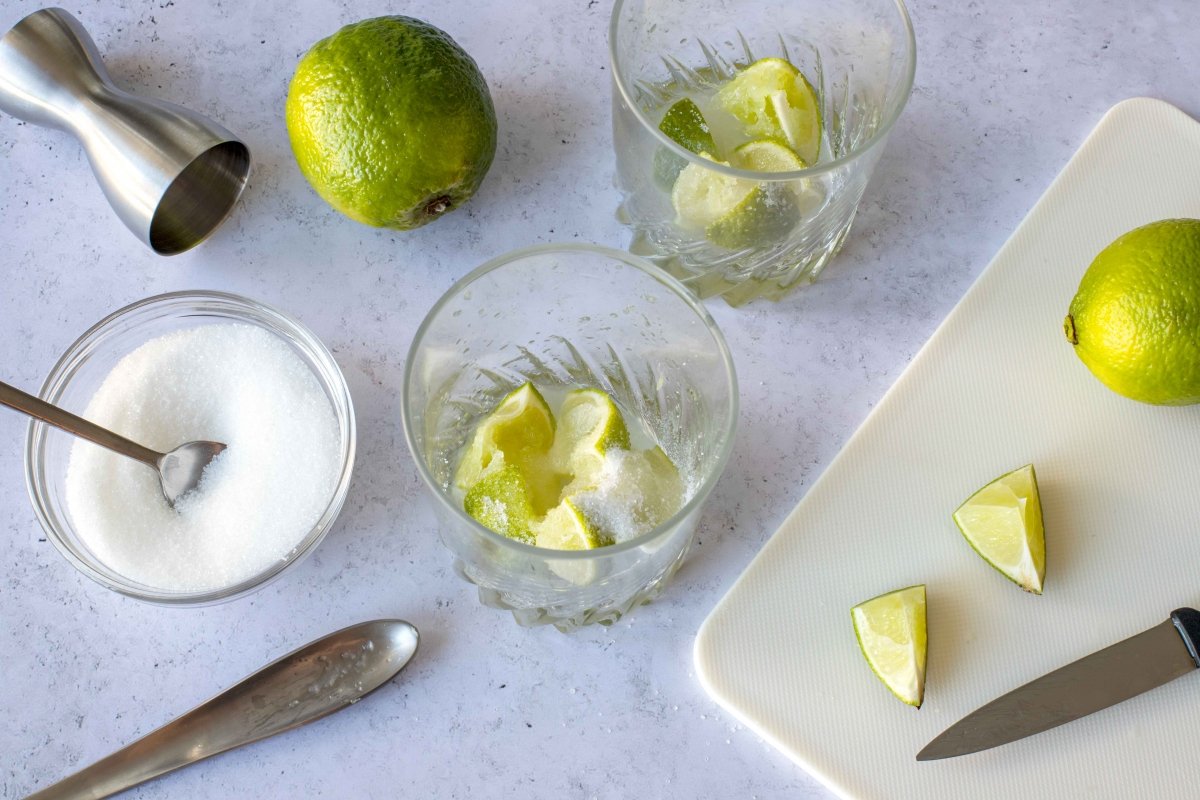 Crush the limes and add the sugar for the caipiroska cocktail