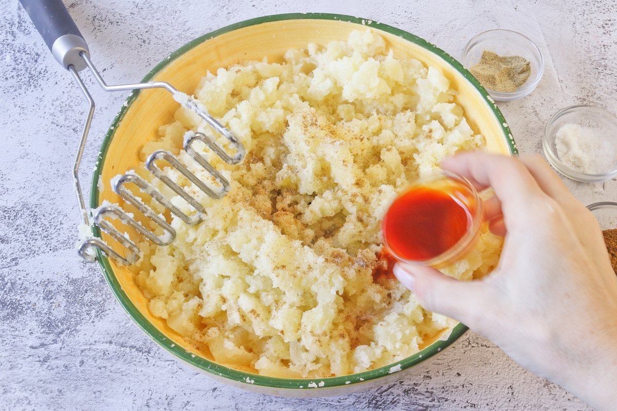 Aplastar y condimentar las patatas para los llapingachos