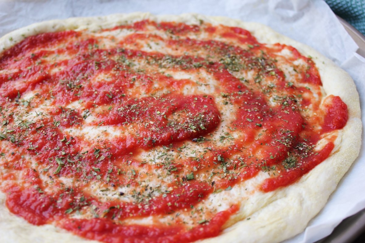 Aspecto de la pizza formada y con la salsa de tomate extendida