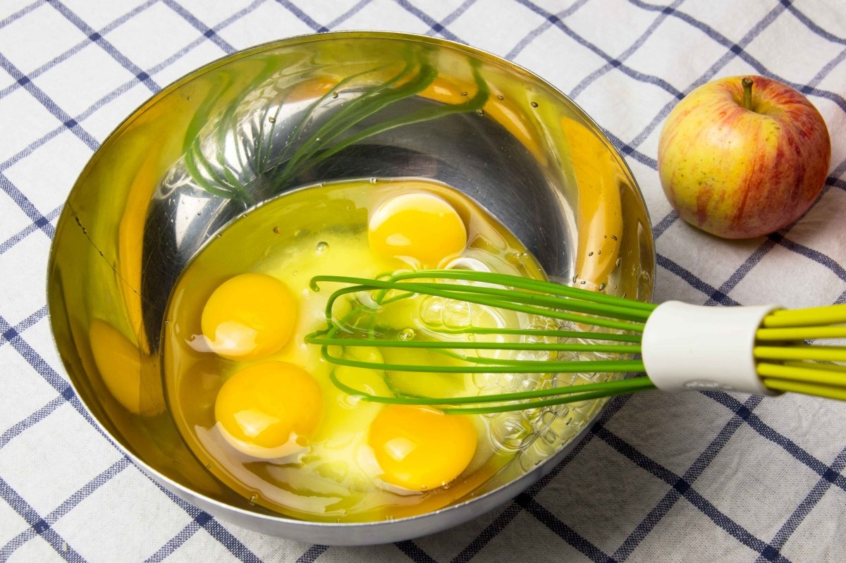 Batir los huevos con el azúcar para hacer el pudding de manzana
