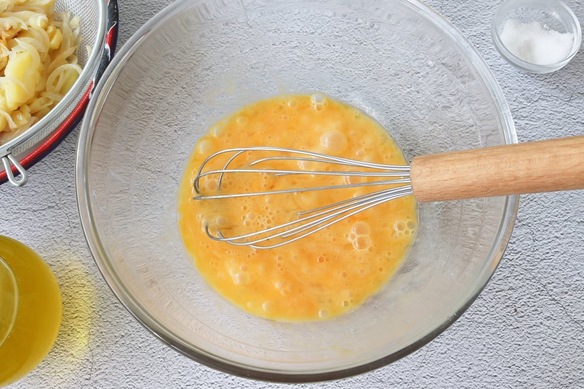 Batir los huevos para la tortilla de patatas con cebolla