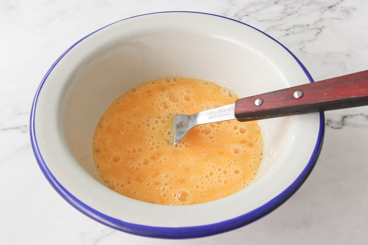 Batir los huevos para la tostada de huevos revueltos con jamón