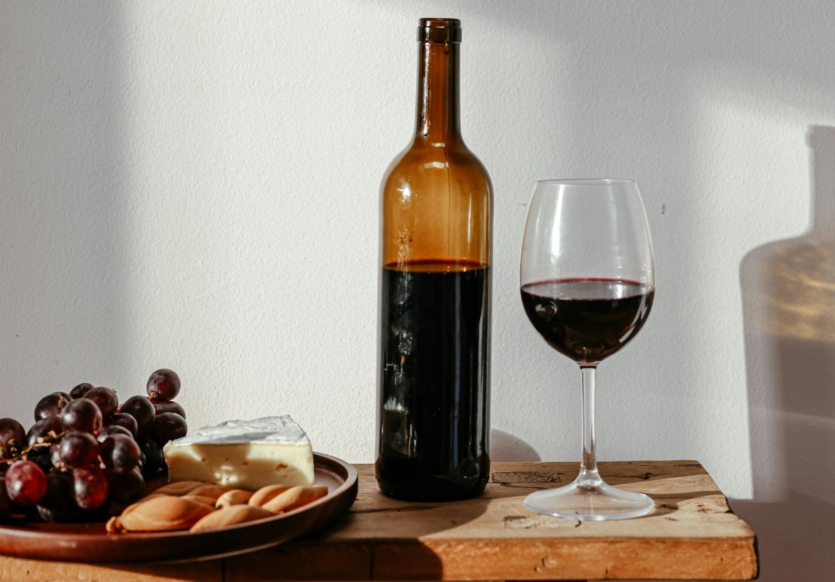 Botella de vino tinto junto a tabla de quesos