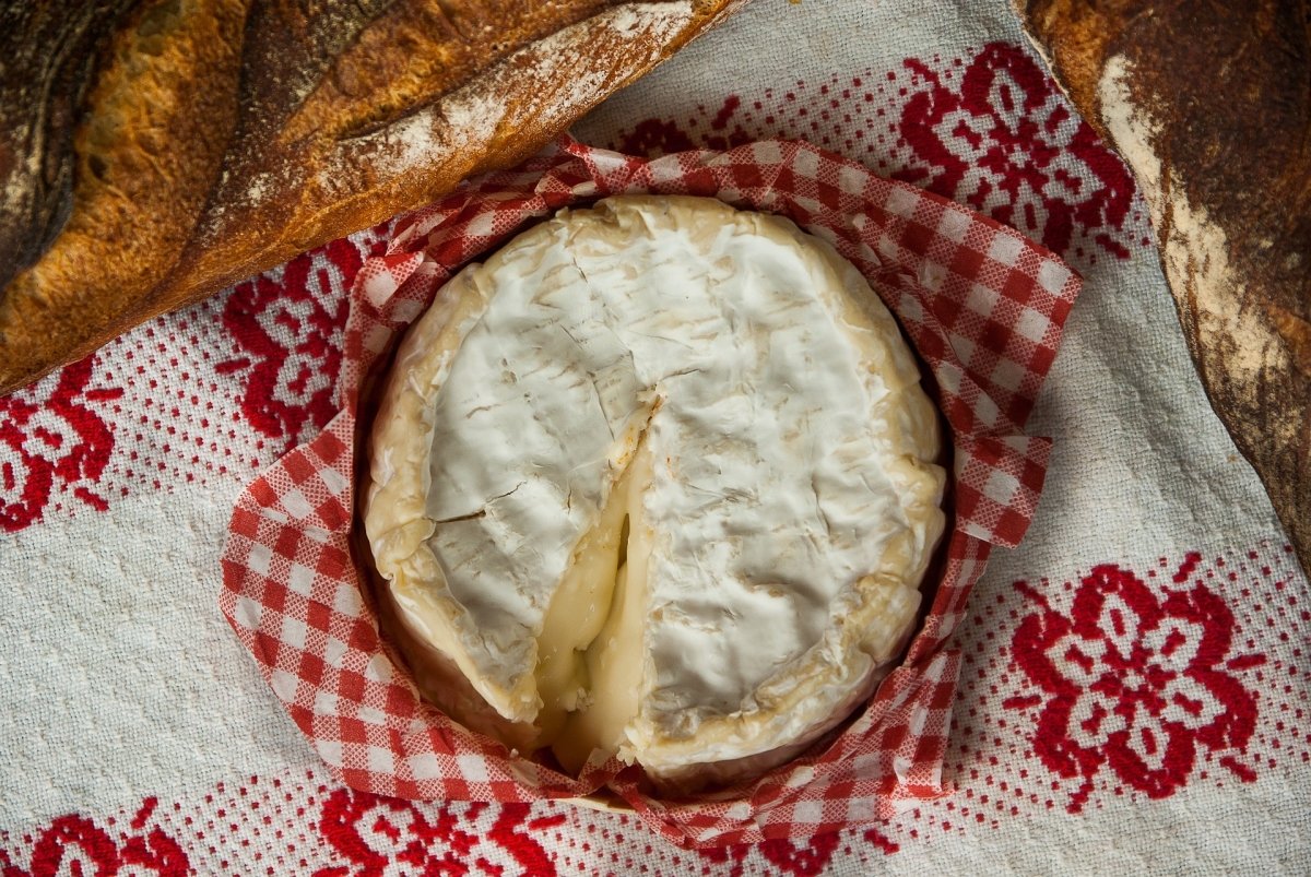 Camembert de Normandía con interior cremoso en bodegón con pan y mantel