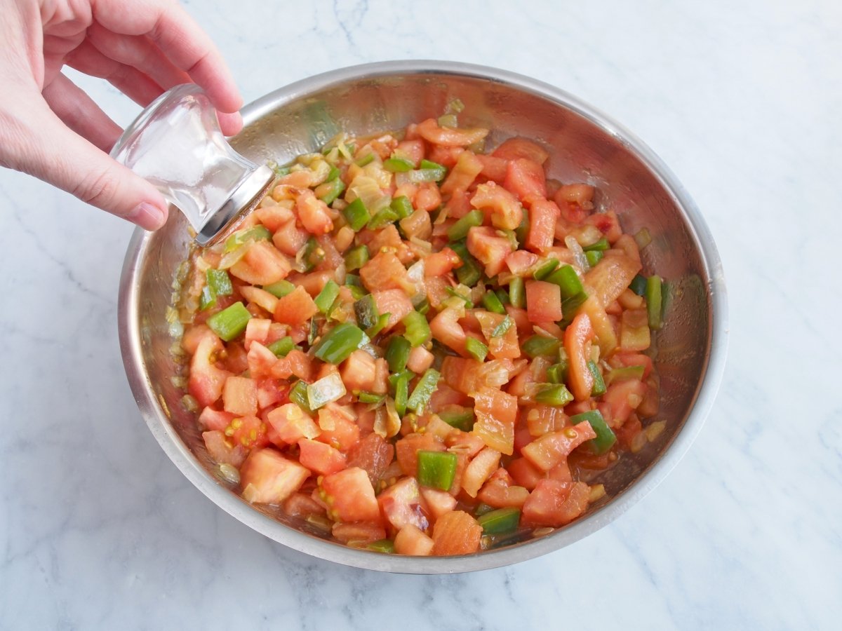 Cebolla y tomates de la fritada de tomates y pimientos guisándose