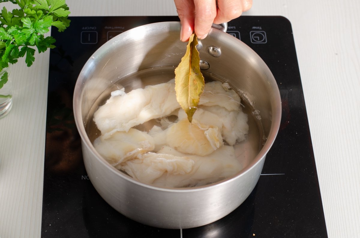 Cocciendo el bacalao desalado para hacer buñuelos de bacalao