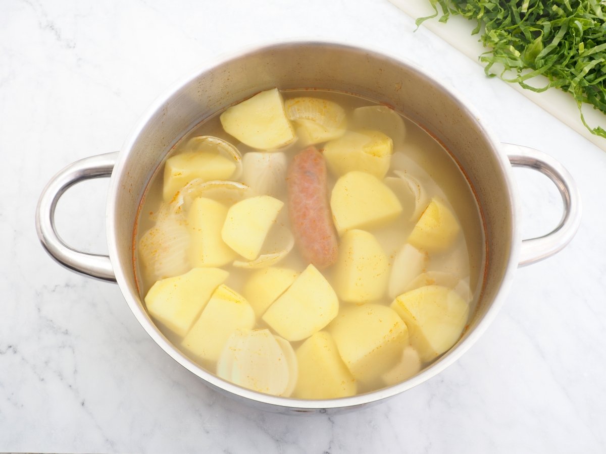 Cocer el chorizo con las patatas y la cebolla