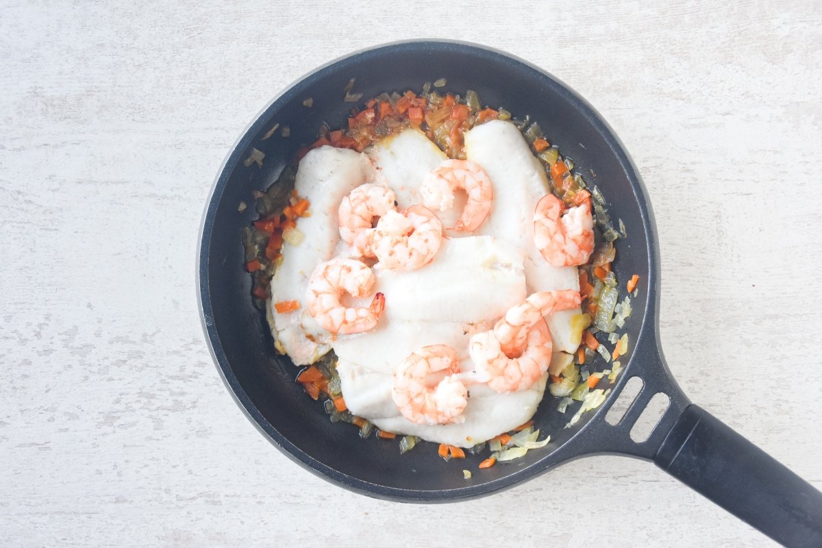 Cocinamos la merluza y las gambas sobre las verduras