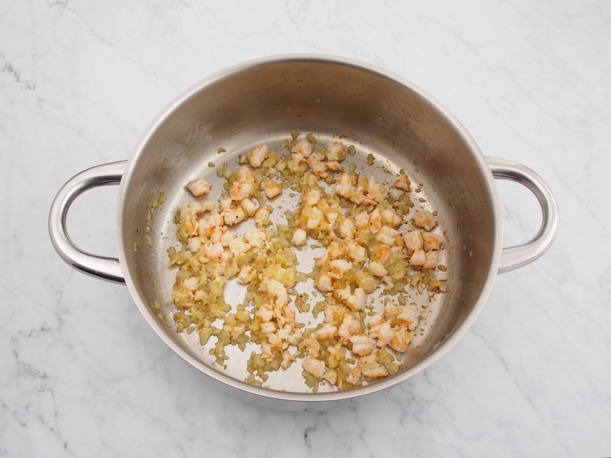 Cocinar la cebolla con los langostinos para los canelones de marisco