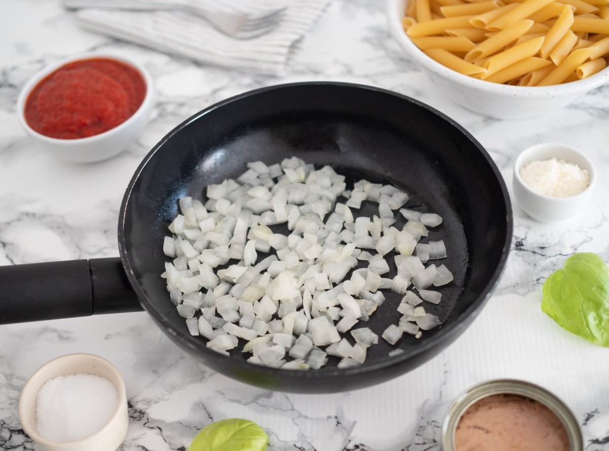 Cocinar la cebolla hasta que quede transparente para los macarrones con atún y tomate