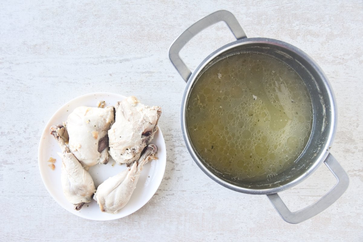 Colamos el caldo y retiramos la piel al pollo