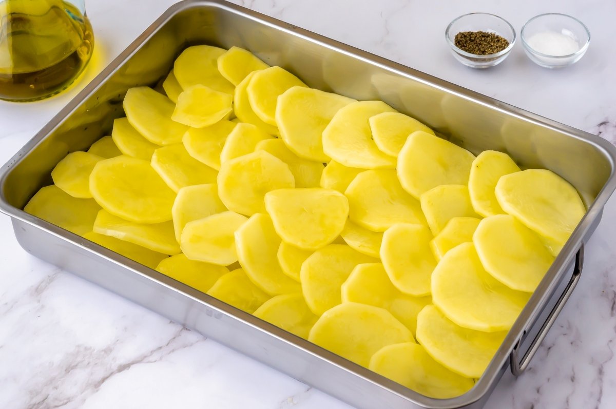 Colocar la capa de patatas para la merluza al horno