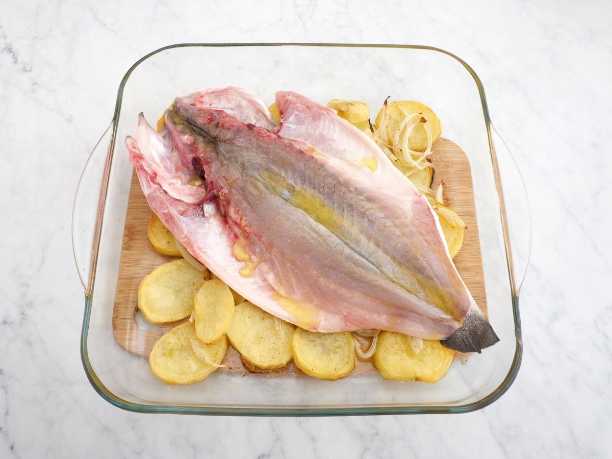 Colocar la lubina abierta a la espalda sobre las patatas