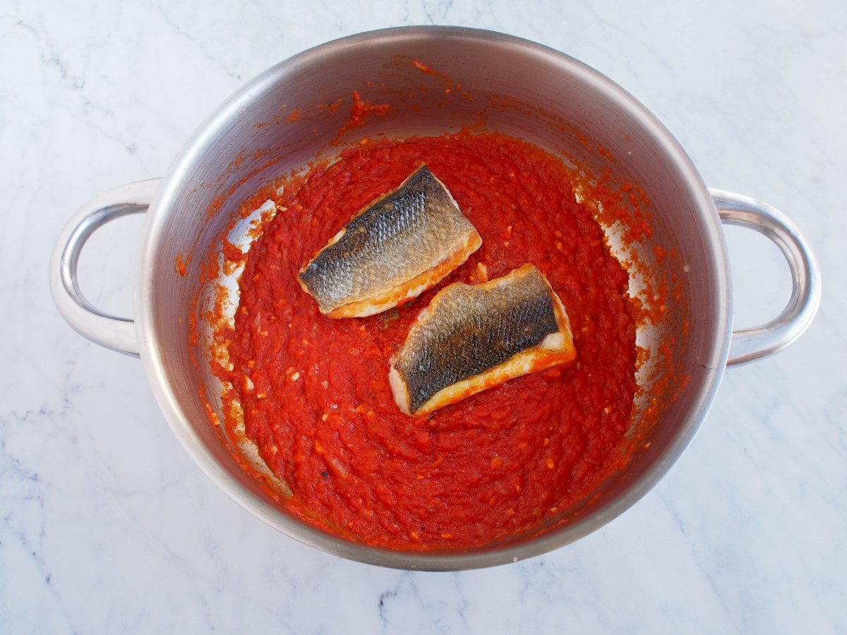 Colocar la lubina en la salsa de tomate con la piel hacia arriba