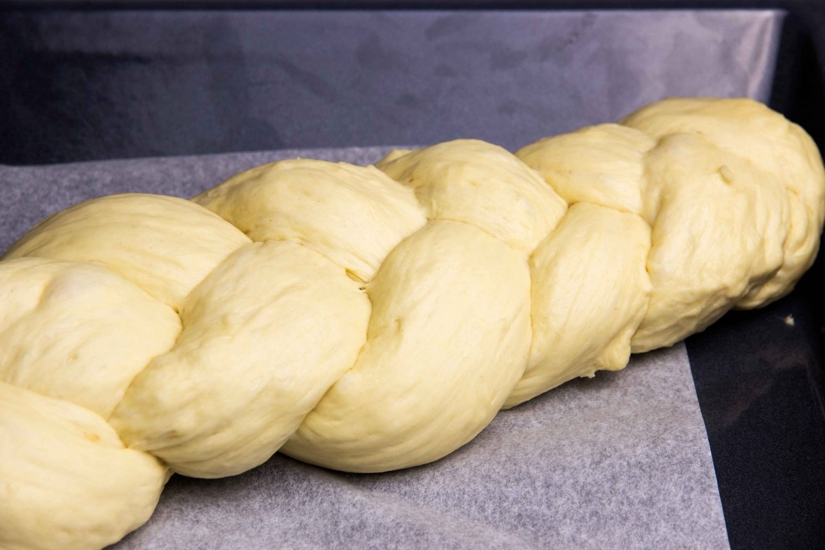 Colocar la masa trenzada para el pan Challah en una bandeja de horno, tapar y reposar 30 minutos