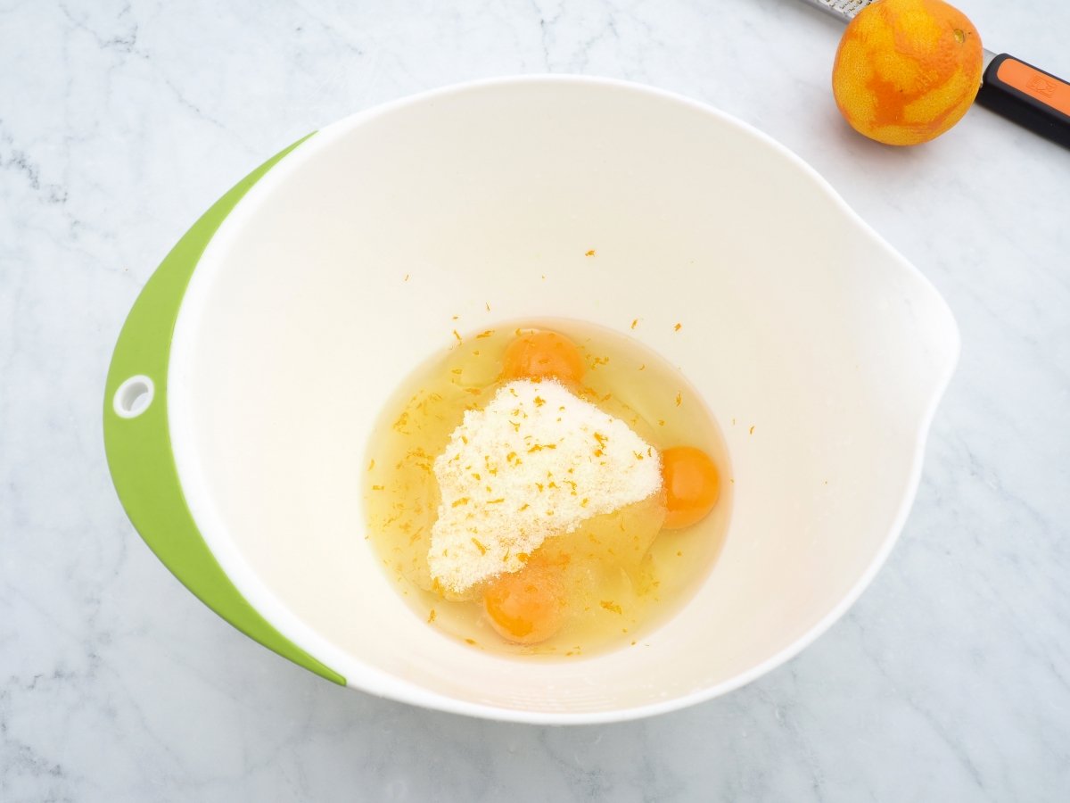 Colocar los huevos con el azúcar y la ralladura de naranja en un bol