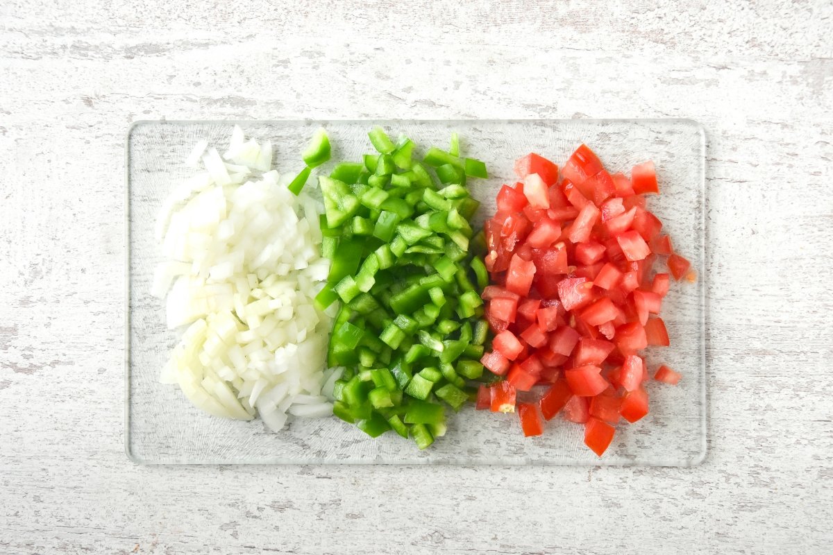Cortamos a daditos la cebolla, el pimiento y el tomate