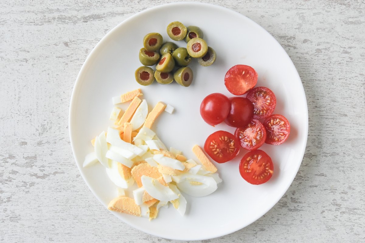 Cortamos el huevo, las olivas y los tomates