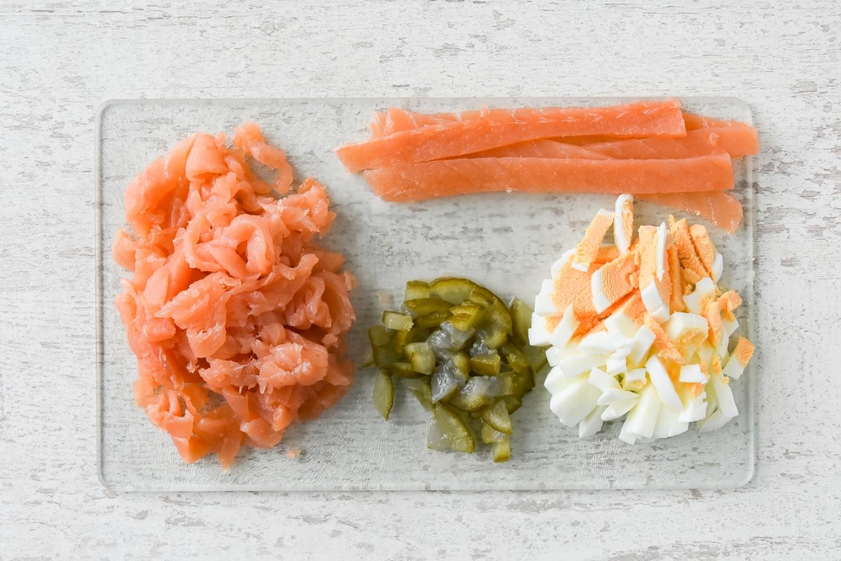 Cortamos el salmón ahumado, los pepinillos y los huevos