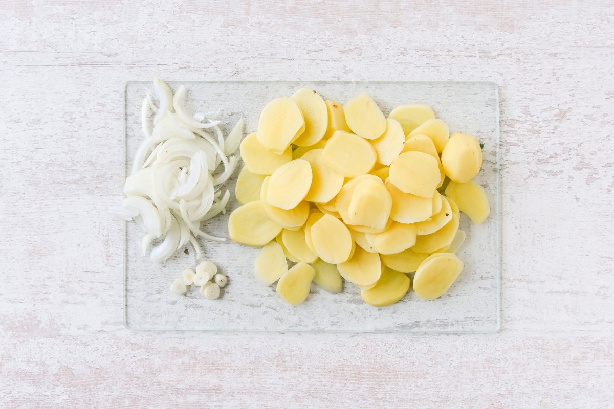 Cortamos las patatas, la cebolla y el ajo para las patatas panaderas