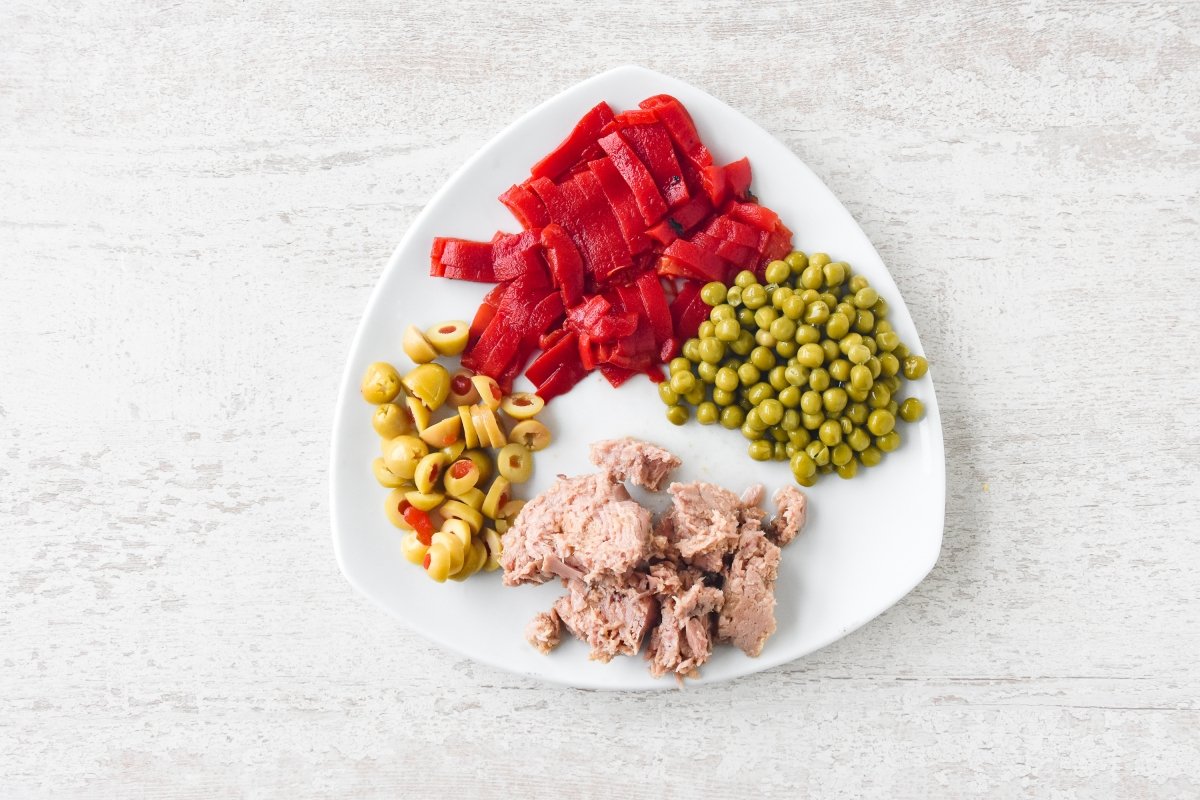 Cortamos los pimientos y aceitunas y escurrimos el atún y los guisantes