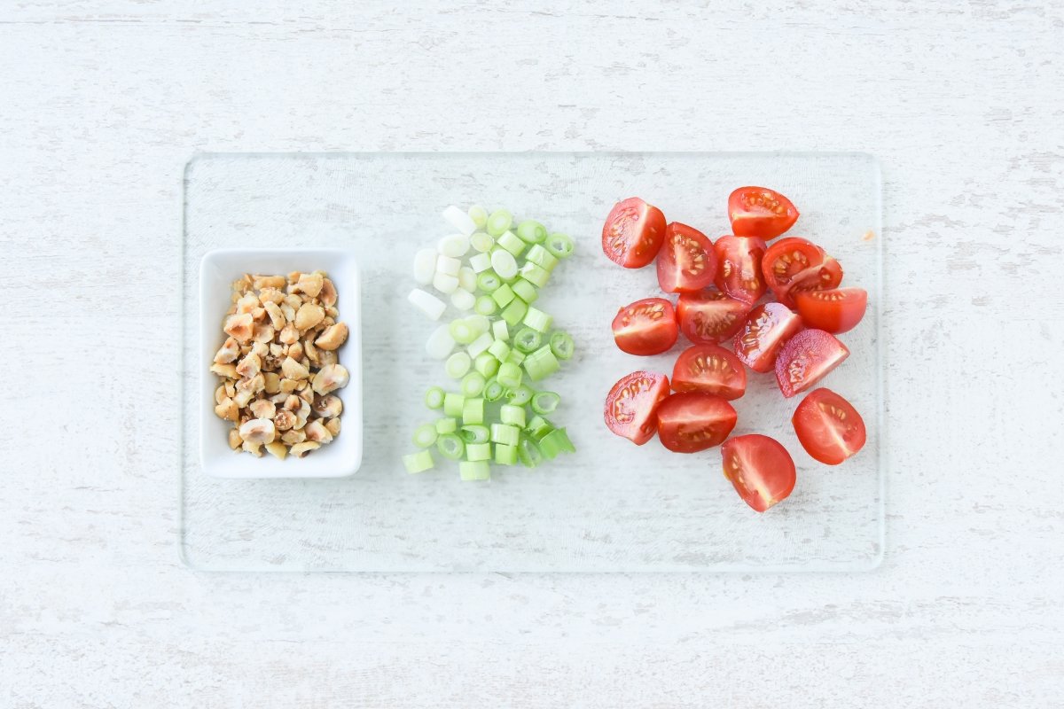 Cortamos los tomates, las cebolletas y las avellanas