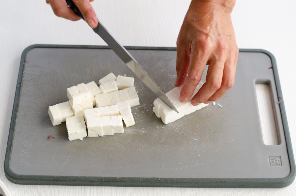 Cortando el queso feta en cubos para la ensalada de garbanzos